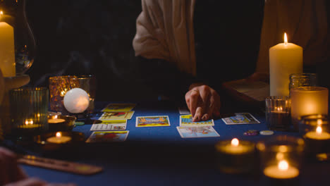 Nahaufnahme-Einer-Frau,-Die-Einem-Mann-Am-Kerzenbeleuchteten-Tisch-Tarotkarten-Vorliest-4